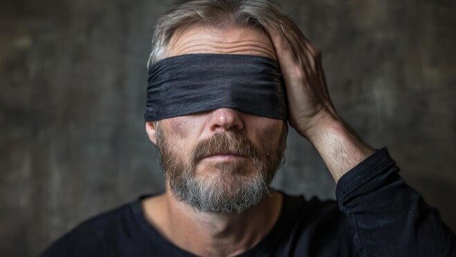 A blindfolded man representing the fear of vision loss, a major diabetic complication.